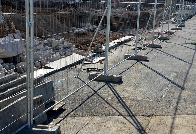 a construction worker assembling temporary fence panels for a job site